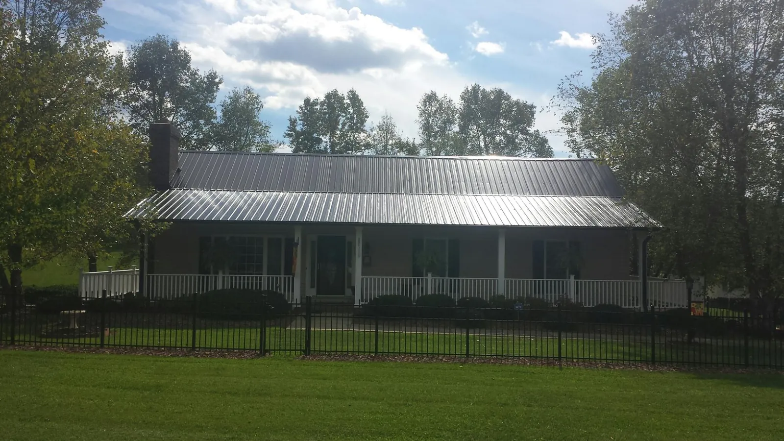 Gray metal roof on a brick ranch with a full width front porch — Gutter Guard Installation work by our crew in Huntington